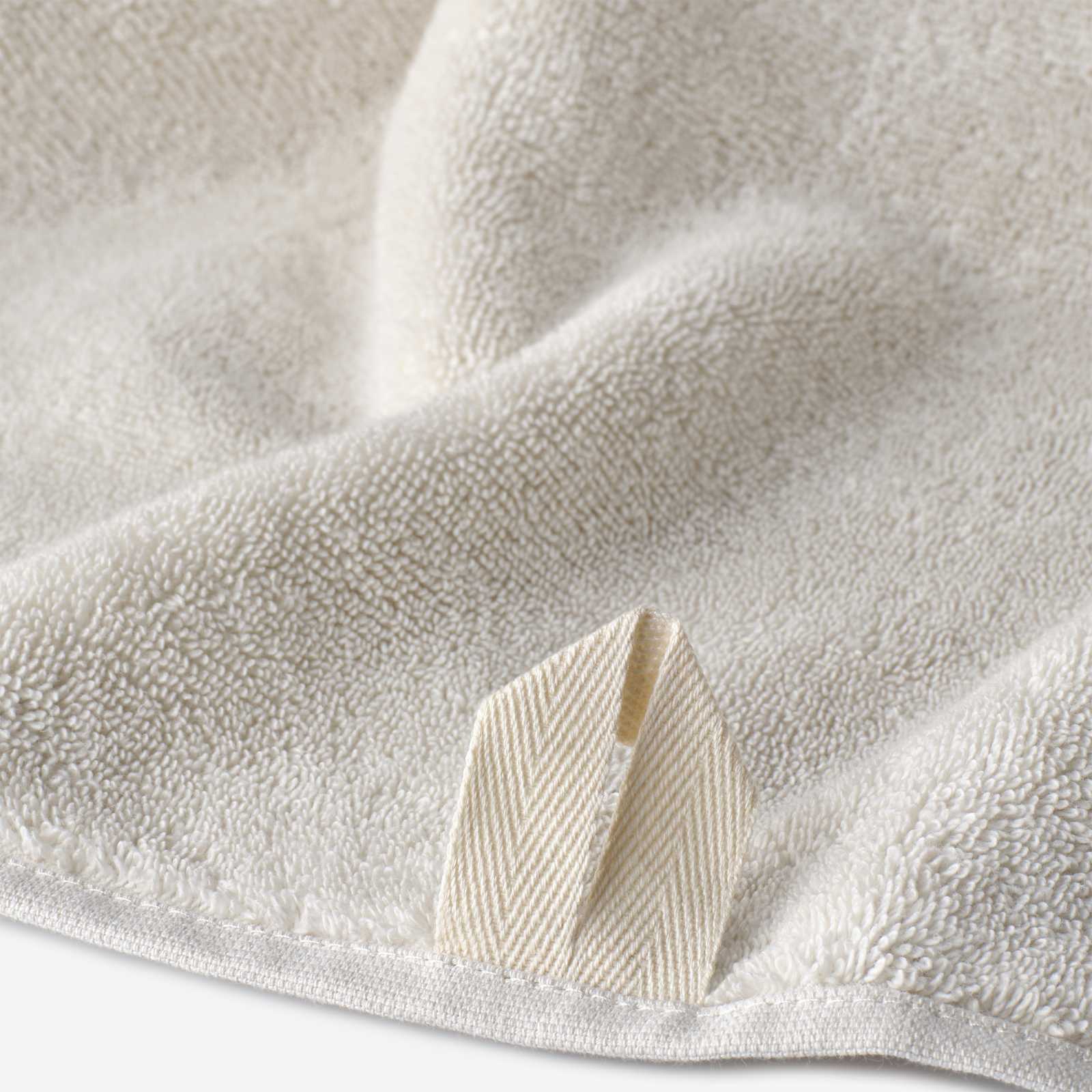 Close-up of a cream cotton towel highlighting the soft terry texture and woven border detail.