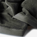 Close-up of a dark olive green cotton towel highlighting the terry texture and ribbed woven border detail.