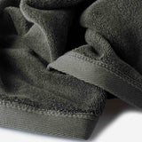 Close-up of a dark olive green cotton towel highlighting the terry texture and ribbed woven border detail.
