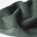 Close-up of a dark green cotton towel highlighting the terry texture and ribbed woven border against a white background.