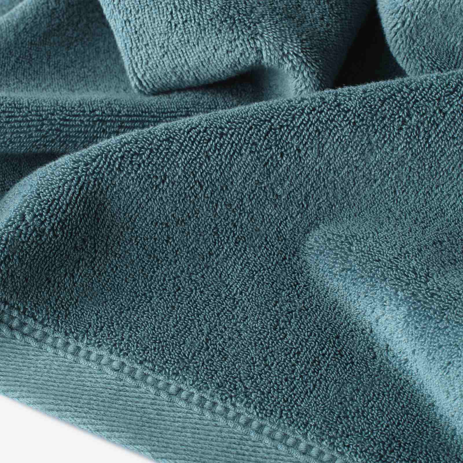 Close-up of a teal cotton towel highlighting the soft terry texture and ribbed woven border detail.