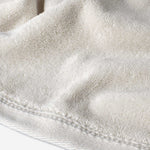 Close-up of a cream cotton towel highlighting the soft terry texture and ribbed woven border detail.