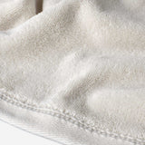 Close-up of a cream cotton towel highlighting the soft terry texture and ribbed woven border detail.