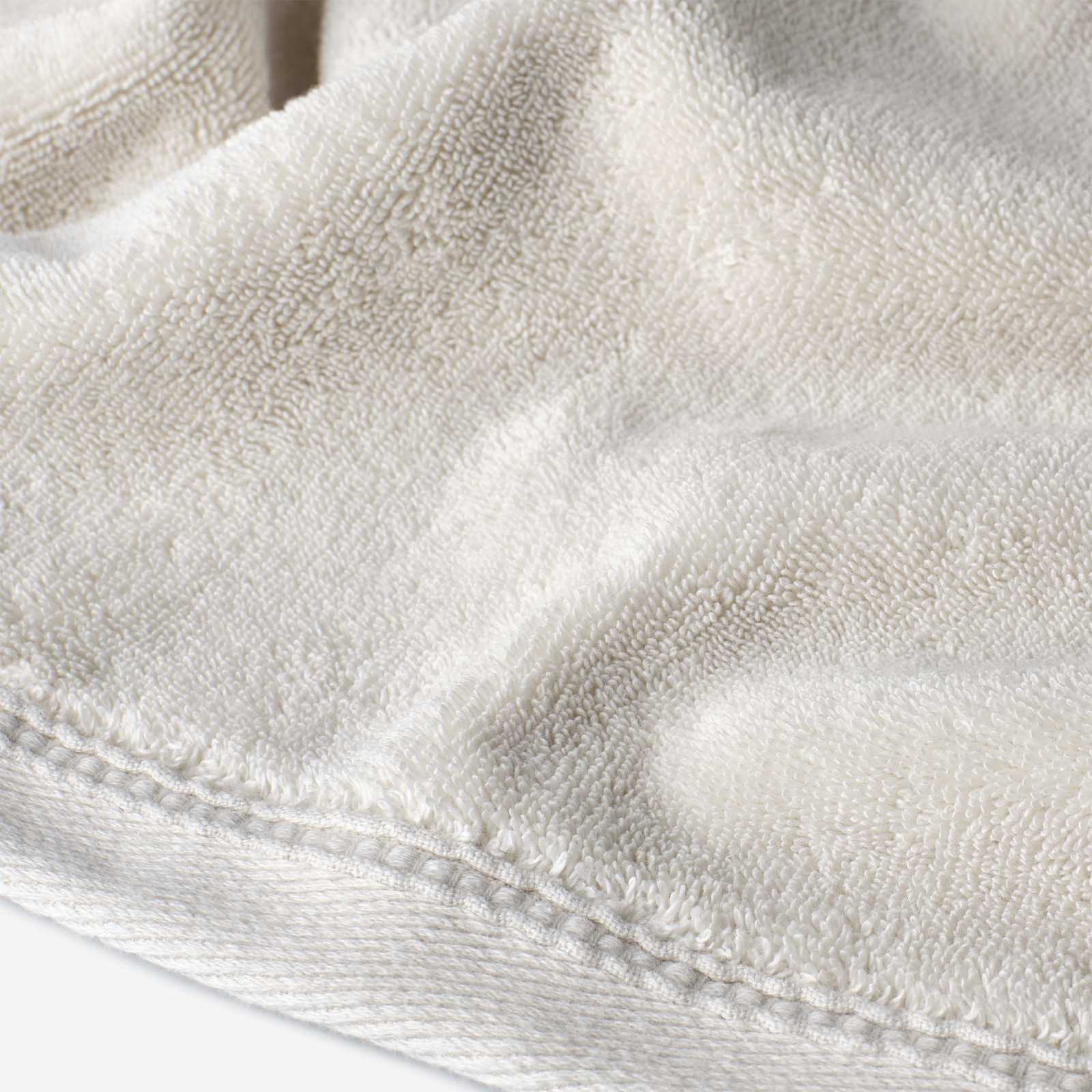 Close-up of a cream cotton towel highlighting the soft terry texture and ribbed woven border detail.