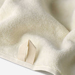 Close-up of a light cream cotton towel highlighting the soft terry texture and integrated beige hanging loop detail.