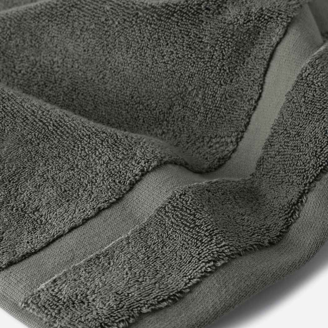 Close-up of a dark gray cotton bath sheet highlighting the dense terry texture and woven border detail.