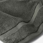 Close-up of a dark gray cotton bath sheet highlighting the dense terry texture and woven border detail.