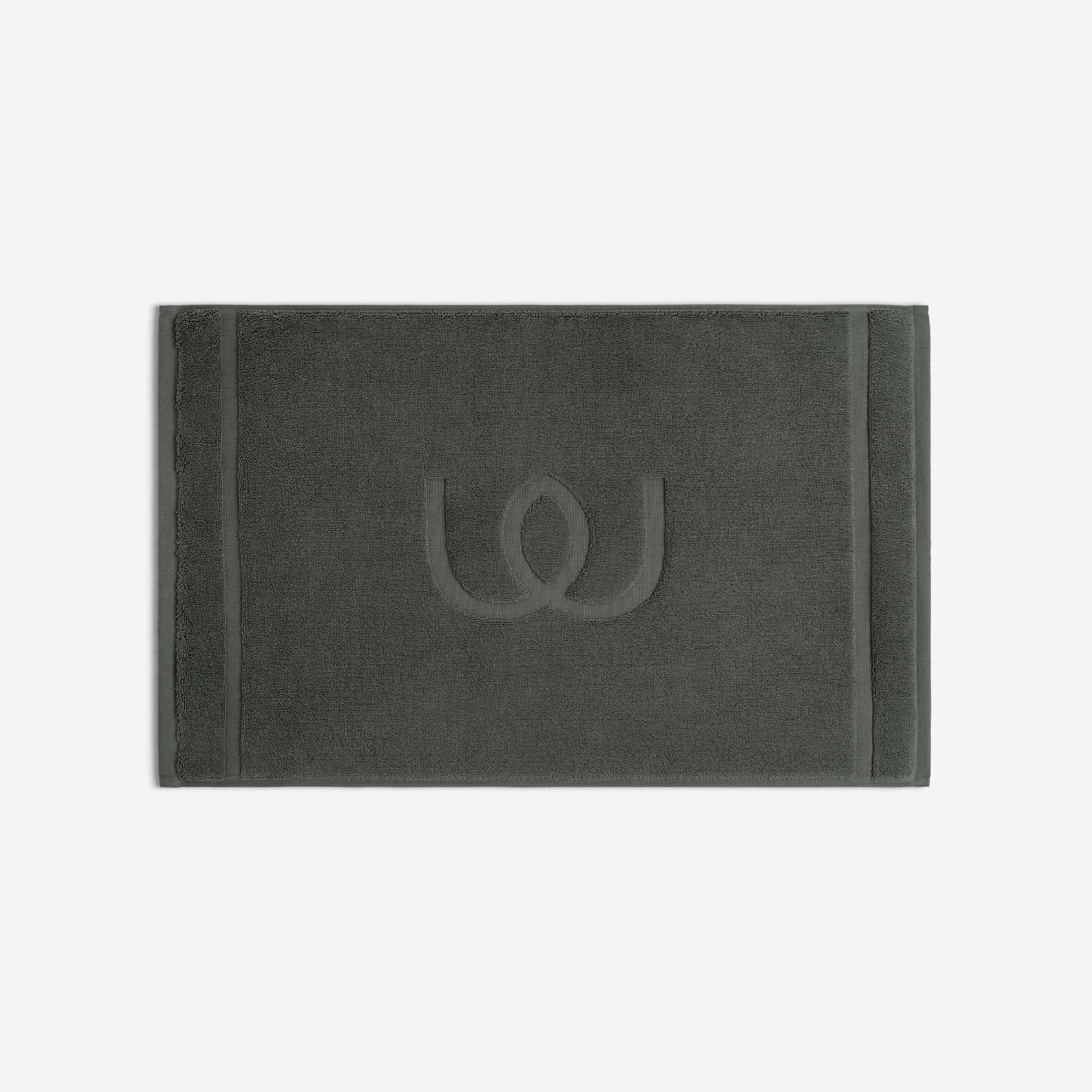 Charcoal gray bath mat with a tonal embroidered logo, shown in horizontal orientation against a white background.