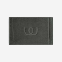 Charcoal gray bath mat with a tonal embroidered logo, shown in horizontal orientation against a white background.
