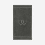 Charcoal gray bath mat with a tonal embroidered logo, shown against a neutral background.