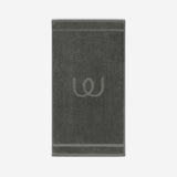 Charcoal gray bath mat with a tonal embroidered logo, shown against a neutral background.