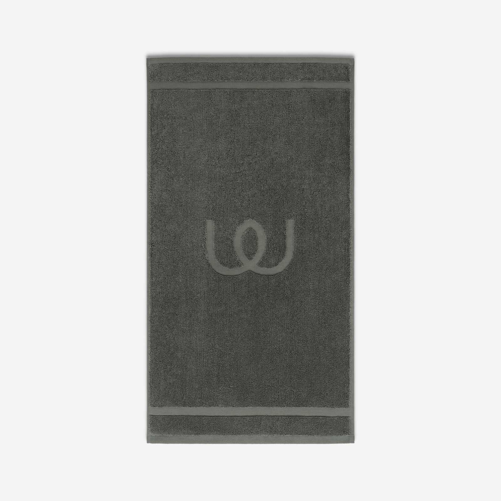 Charcoal gray bath mat with a tonal embroidered logo, shown against a neutral background.