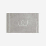 Light gray bath mat with a tonal embroidered logo, shown in horizontal orientation against a white background.