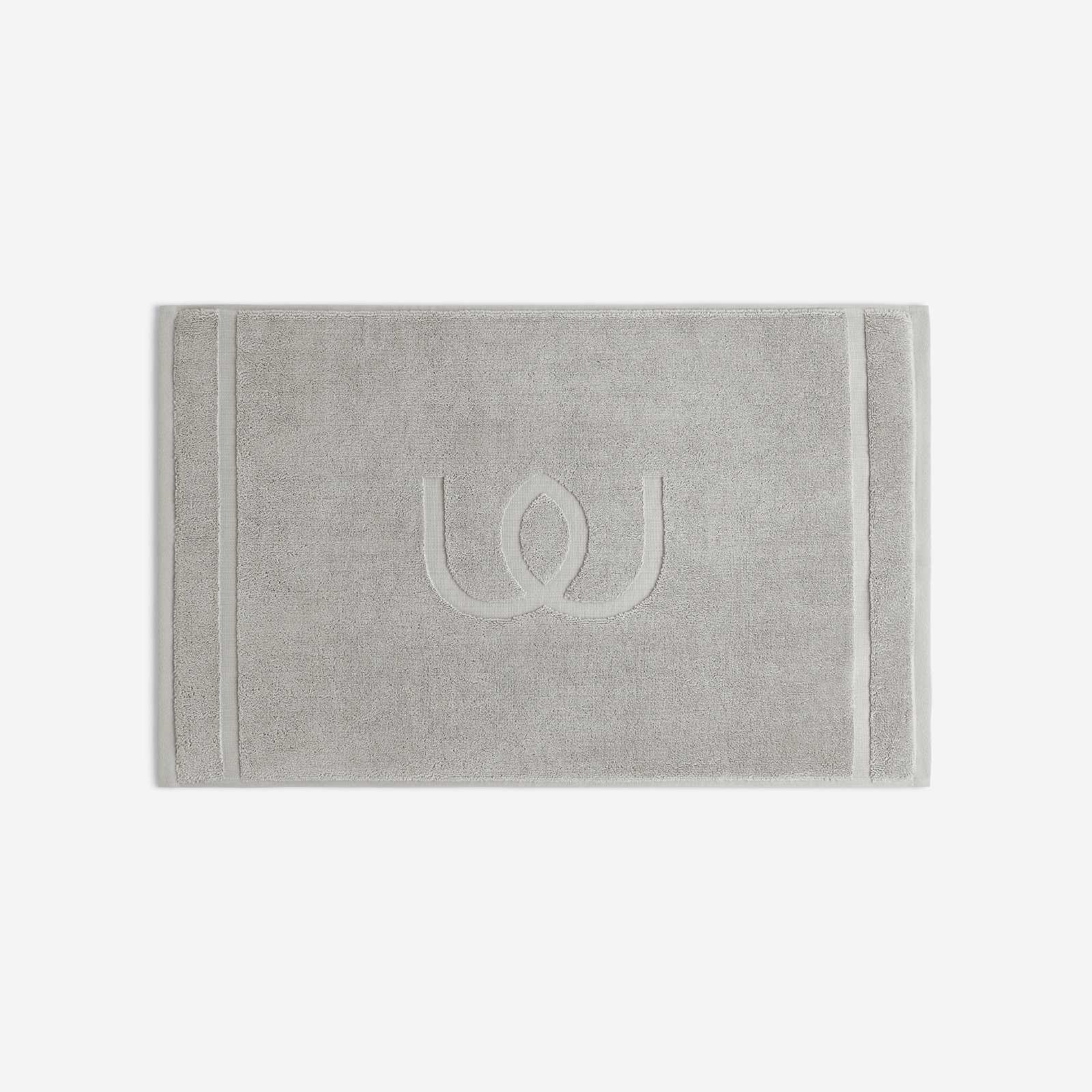 Light gray bath mat with a tonal embroidered logo, shown in horizontal orientation against a white background.