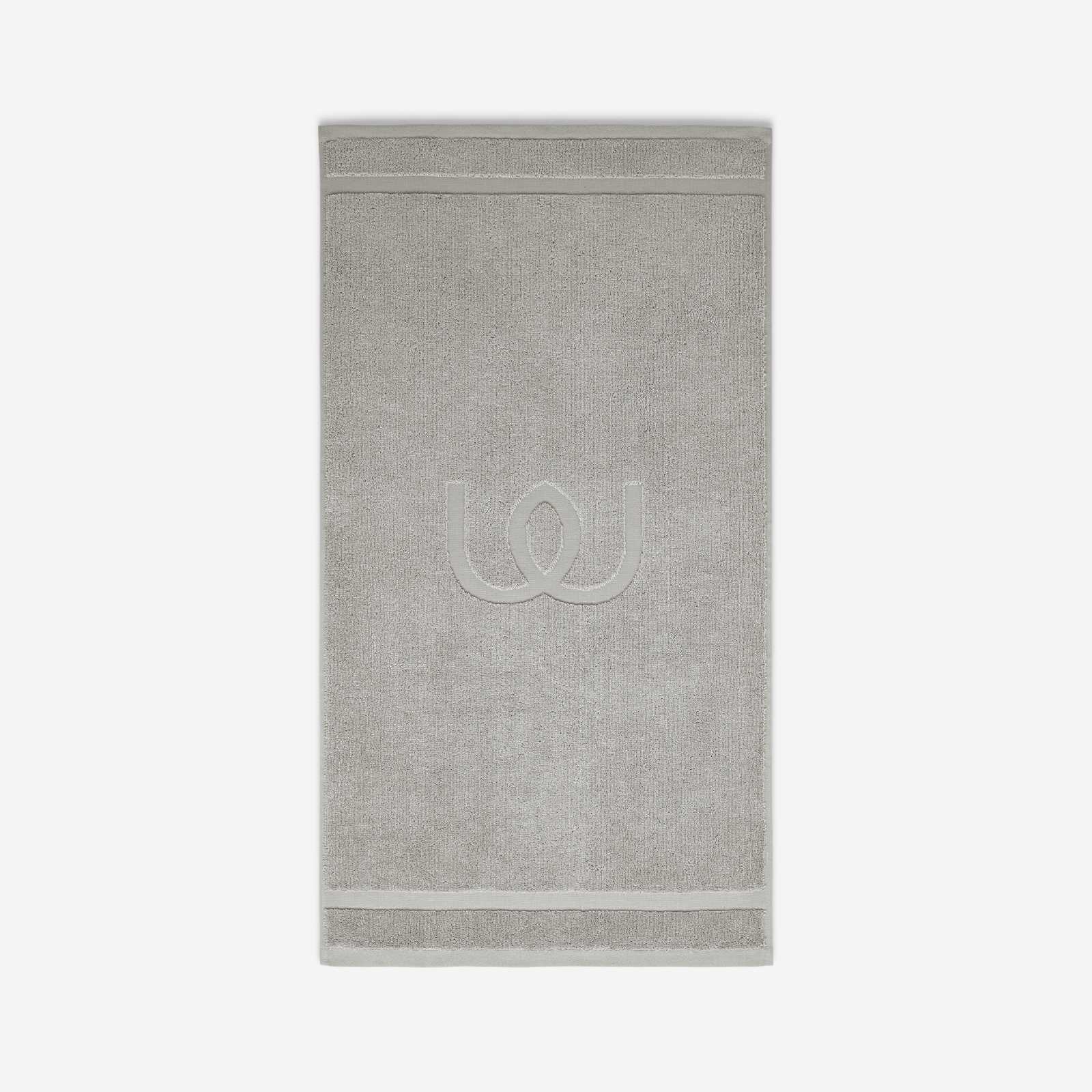 Light gray bath mat with a tonal embroidered logo, shown against a white background.