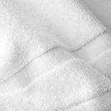 Close-up of a white cotton bath sheet highlighting the dense terry texture and woven border detail.