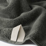 Close-up of a charcoal gray cotton bath sheet highlighting the terry texture and integrated hanging loop detail.
