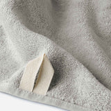 Close-up of a light gray cotton bath sheet highlighting the terry texture and integrated hanging loop detail.