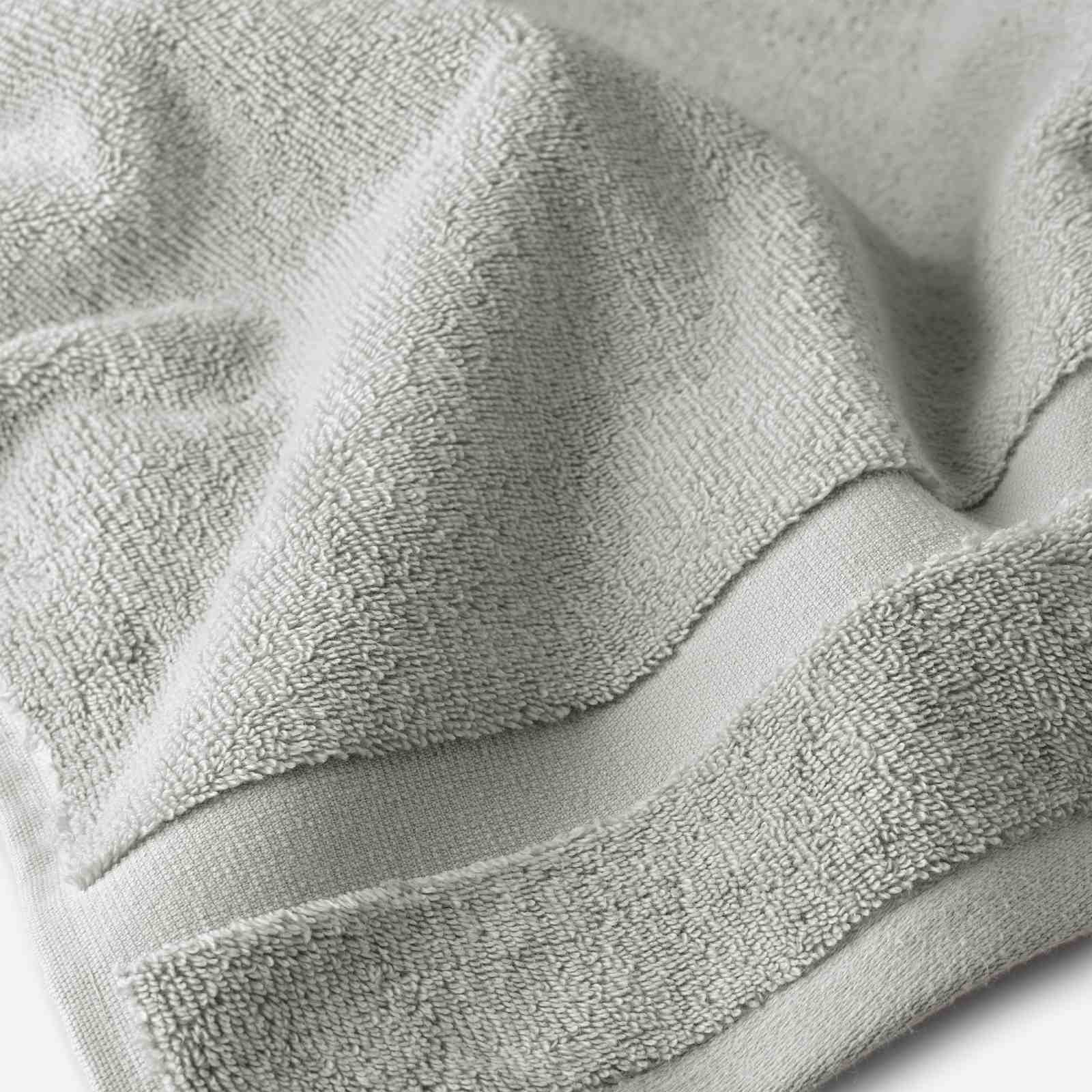 Close-up of a light gray cotton bath sheet highlighting the dense terry texture and woven border detail.