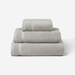 Stack of three light gray cotton towels in different sizes, shown against a white background.