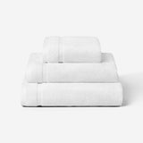 Stack of three white cotton towels in different sizes, shown against a white background.