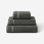Stack of three charcoal gray cotton towels in different sizes, shown against a white background.