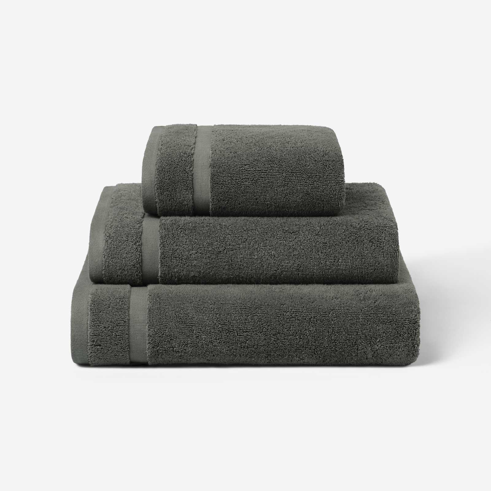 Stack of three charcoal gray cotton towels in different sizes, shown against a white background.