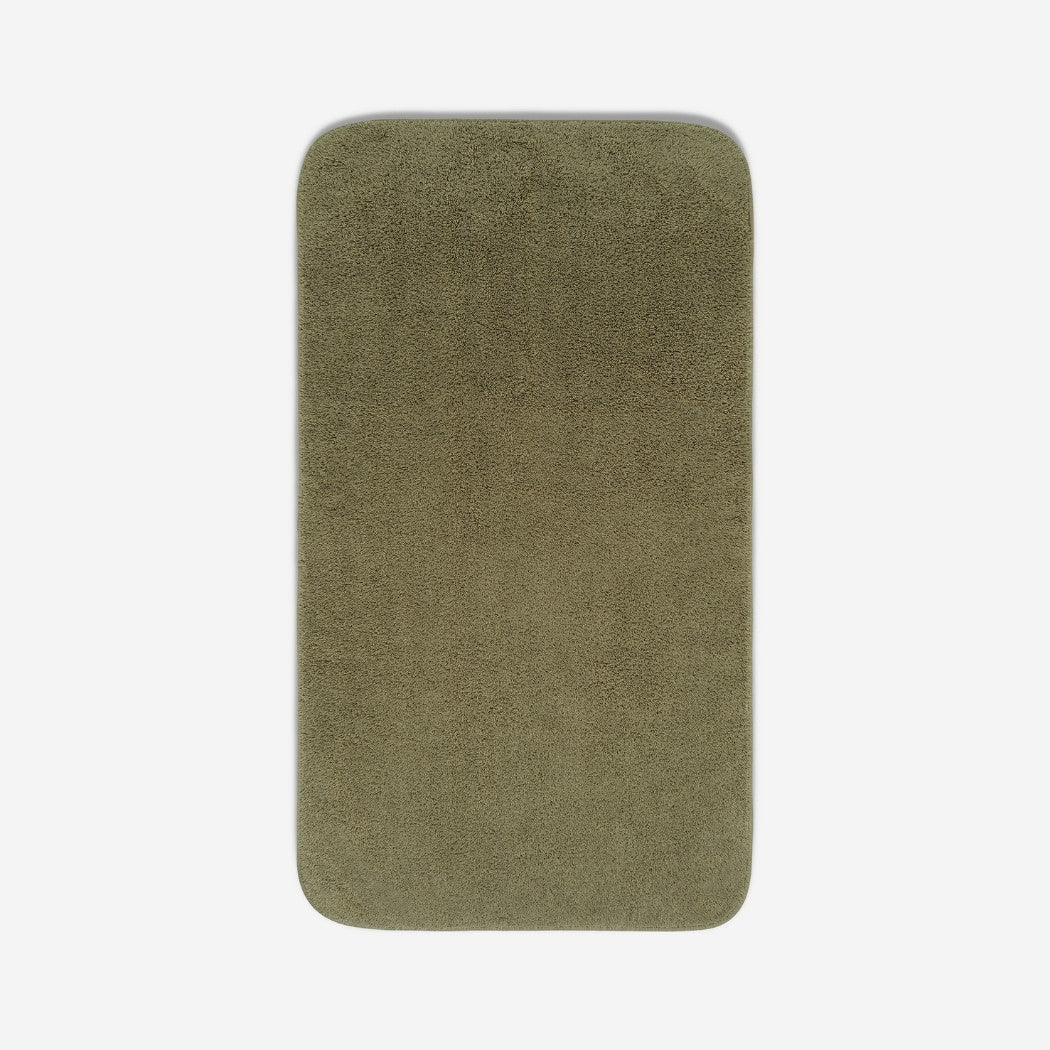 Top view of a dark olive green towel laid flat on a light background, with rounded corners and a small embroidered logo in the lower corner.