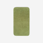 Top view of a green green bath towel laid flat on a light background, with rounded corners and a small embroidered logo in the lower corner.