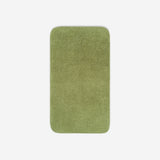 Top view of a green green bath towel laid flat on a light background, with rounded corners and a small embroidered logo in the lower corner.
