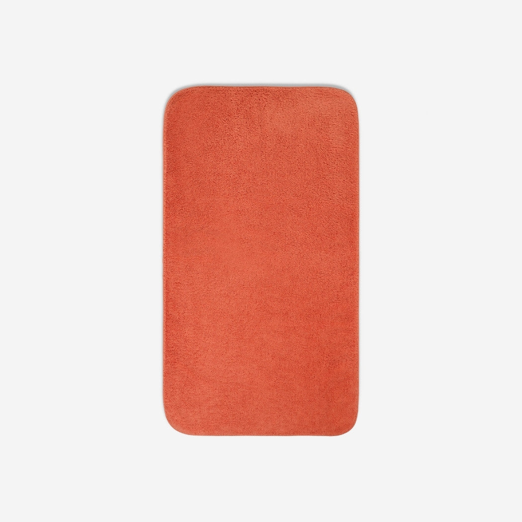 Top view of an orange organic cotton bath towel with rounded corners, displayed flat on a white background.