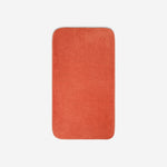 Top view of an orange organic cotton bath towel with rounded corners, displayed flat on a white background.