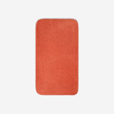 Top view of an orange organic cotton bath towel with rounded corners, displayed flat on a white background.