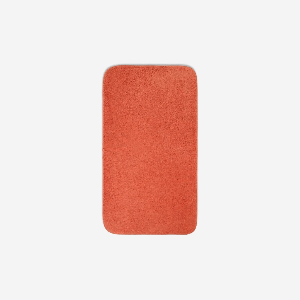 Top view of an orange organic cotton face towel with rounded corners, displayed flat on a white background.
