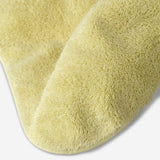 Close-up of a yellow cotton towel highlighting the soft terry texture, rounded corner finish, and subtle embroidered logo detail.