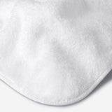 Close-up of a white cotton towel highlighting the soft terry texture, rounded corner finish, and subtle embroidered logo detail.