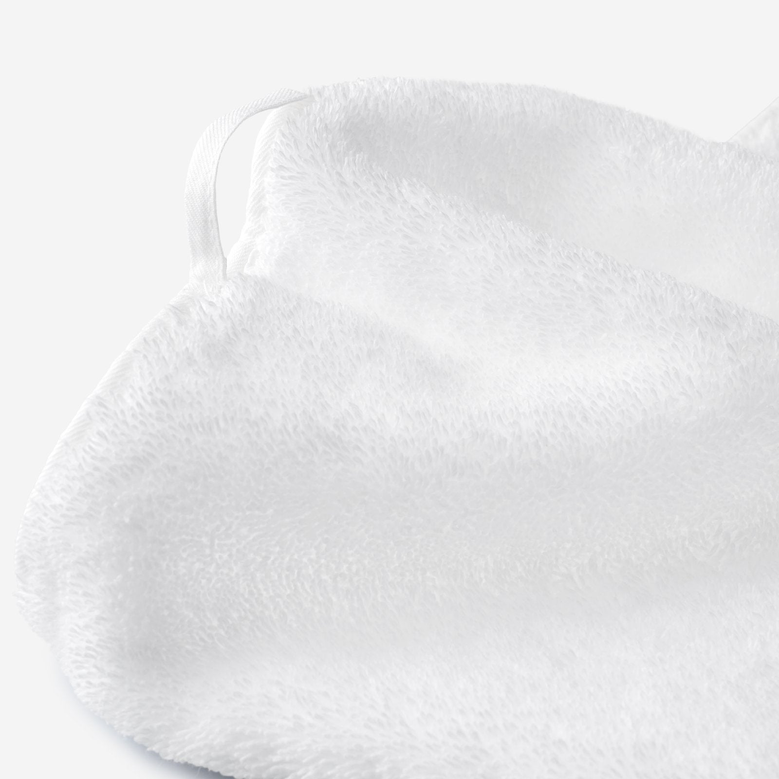 Close-up of a white cotton towel highlighting the soft terry texture and integrated white hanging loop detail.