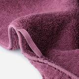 Close-up of a cotton towel showing dense plush pile, reinforced edge binding, and an integrated hanging loop.