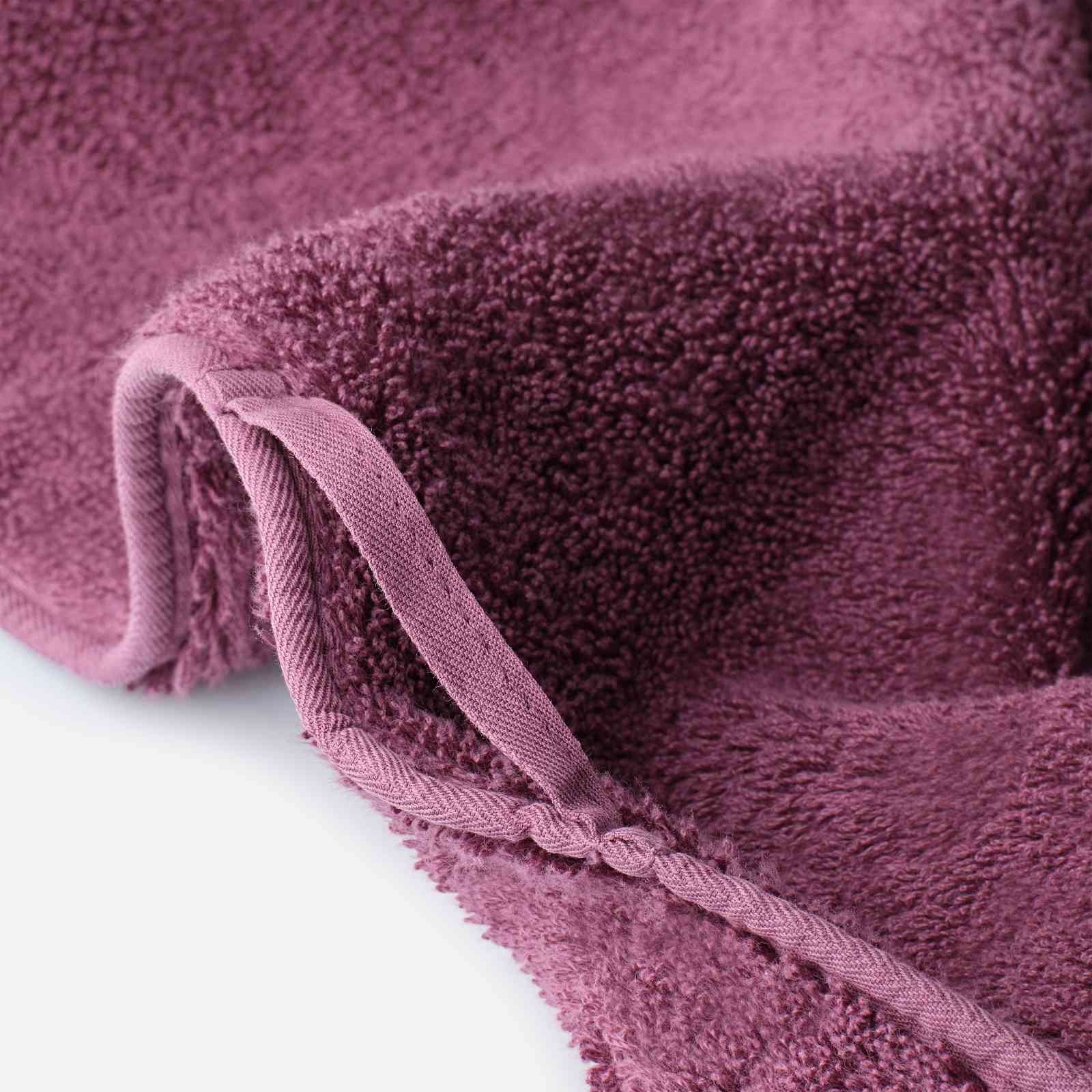 Close-up of a cotton towel showing dense plush pile, reinforced edge binding, and an integrated hanging loop.