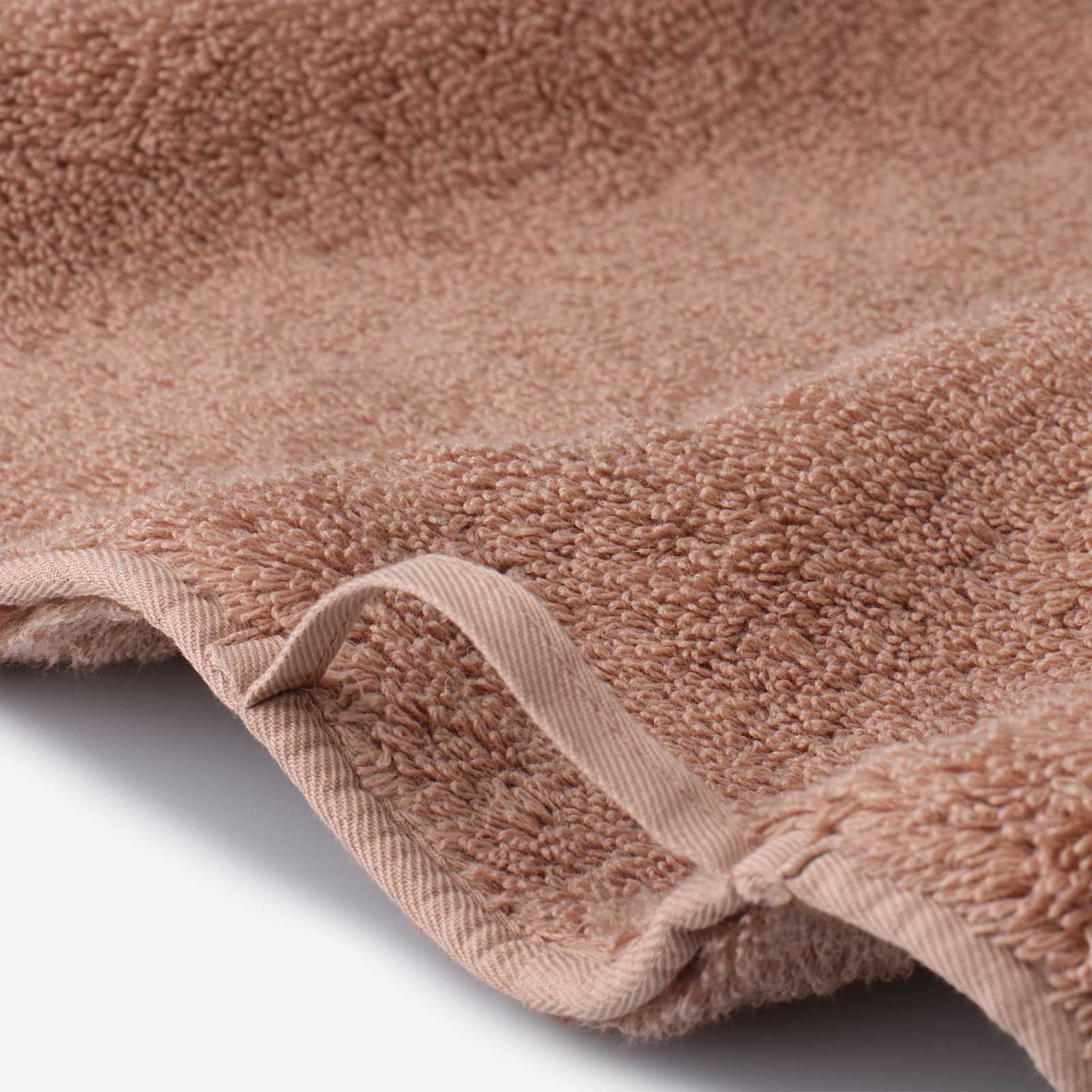 Close-up detail of a dusty rose cotton towel featuring soft plush pile, reinforced edge binding, and a practical hanging loop.