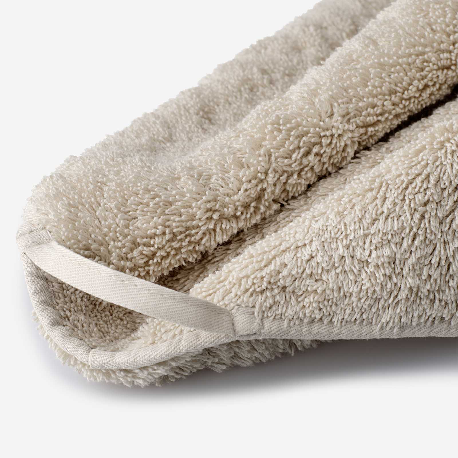 Close-up of a beige cotton towel highlighting the soft terry texture and integrated matching hanging loop detail.
