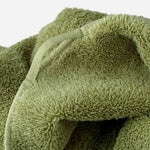 Close-up of an olive green towel showing the terry texture and a fabric hanging loop stitched into the edge seam.