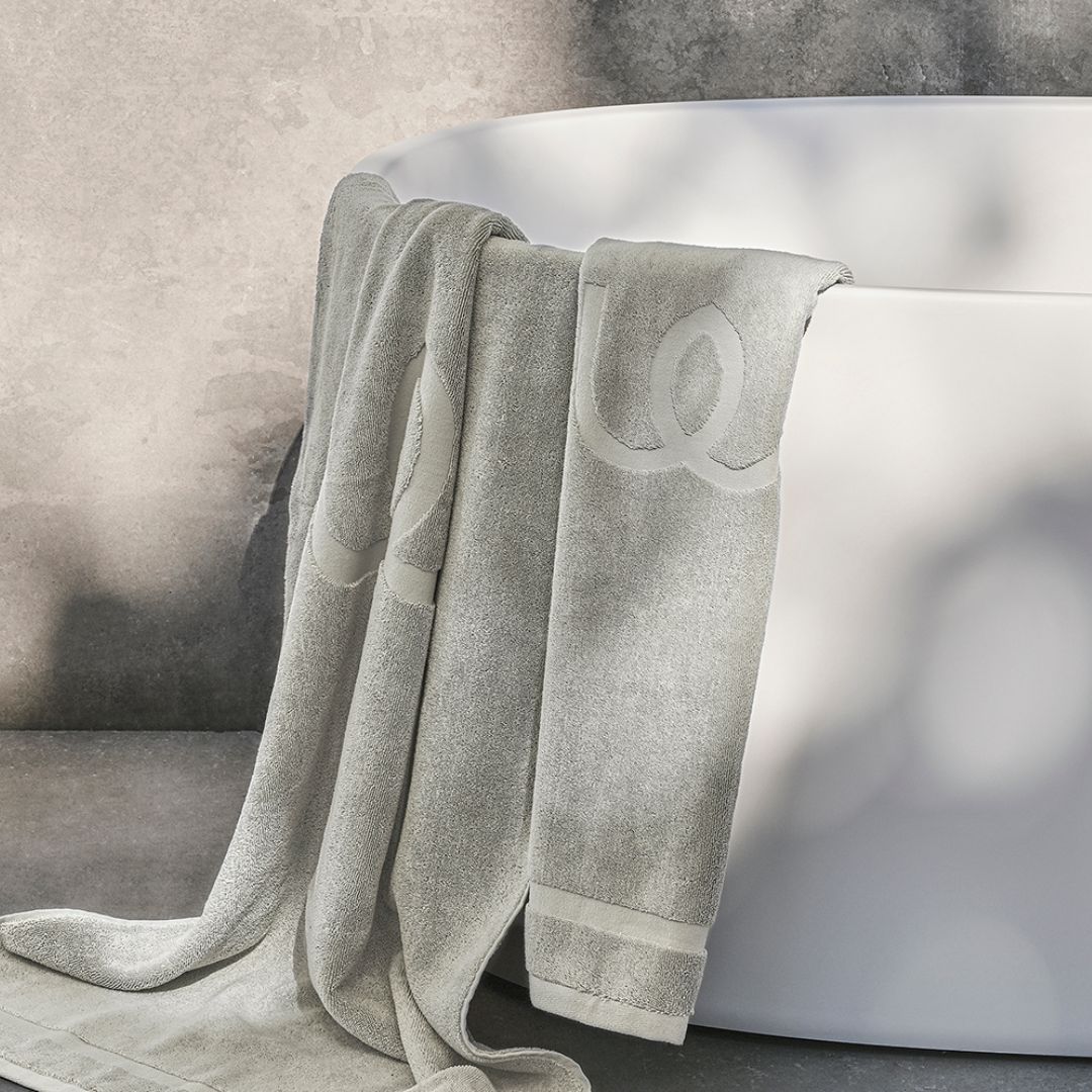 Gray towel draped over a white bathtub with a neutral background.