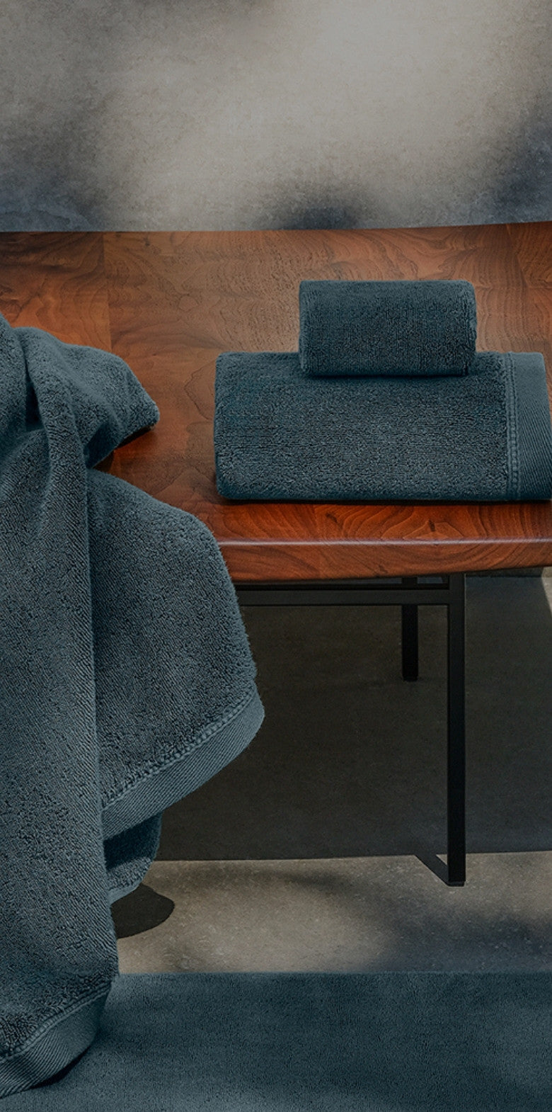 Blue bath towels folded and draped on a wooden bench