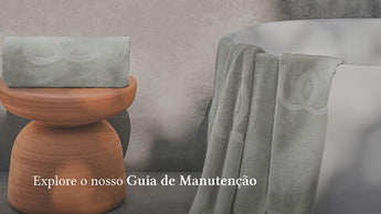 Grey bath towels with jacquard logo displayed beside a white bathtub and terracotta stool