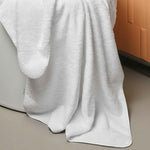 White towel draped over a bathtub with an orange cushioned backrest.