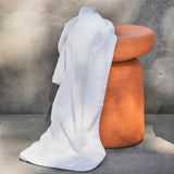 White towel draped over a wooden stool against a gray background