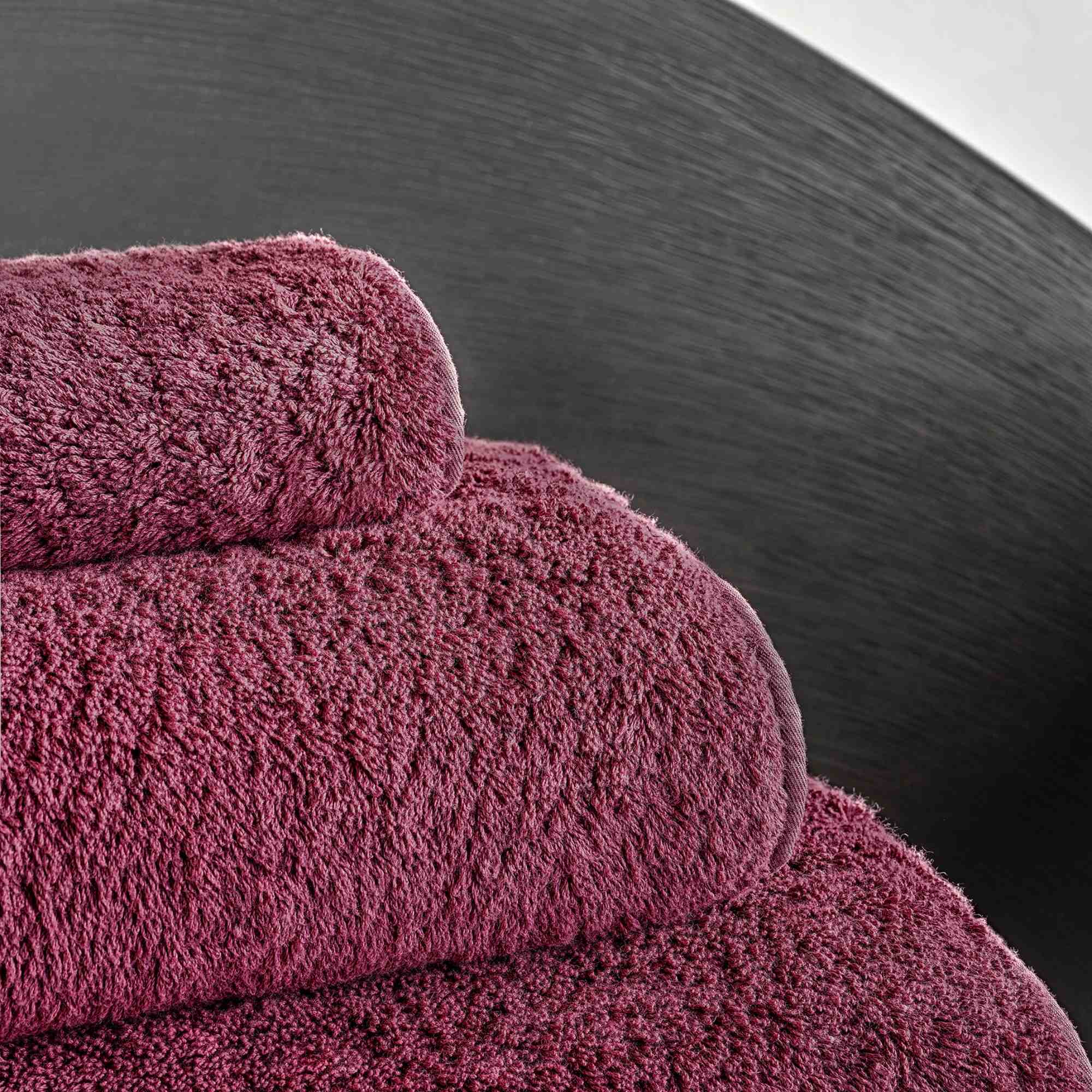 Stack of burgundy towels on a dark surface