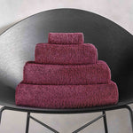 Stack of purple towels on a black chair against a light gray background.