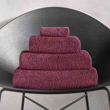 Stack of purple towels on a black chair against a light gray background.